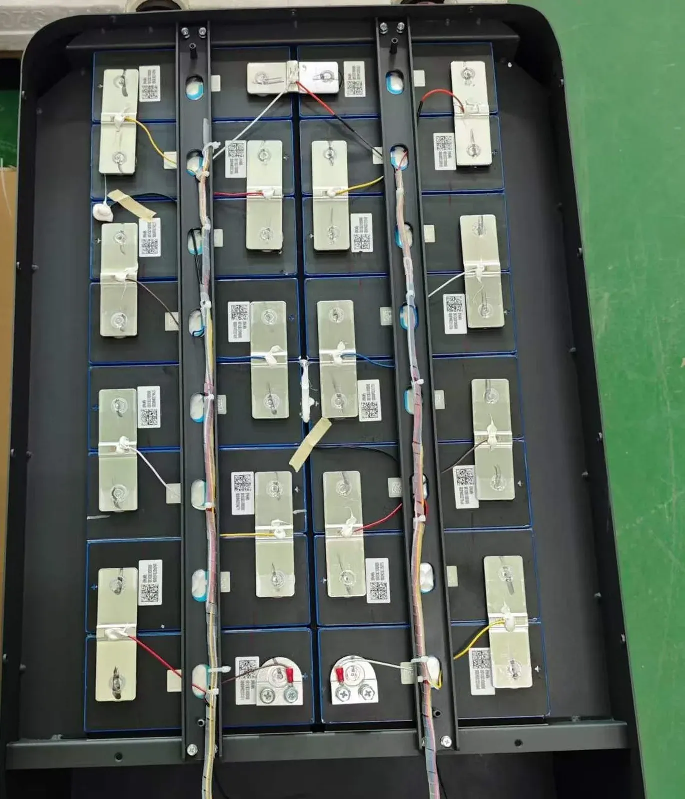 Top-down view of laser-welded battery pack showing cell QR codes remaining fully visible beside busbar connections